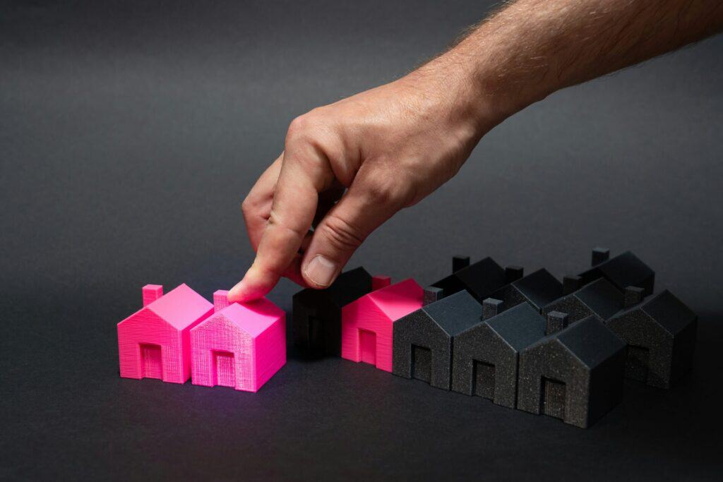 A hand pointing at a pink house on a black background