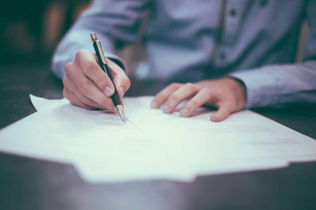A person is writing on a piece of paper with a pen